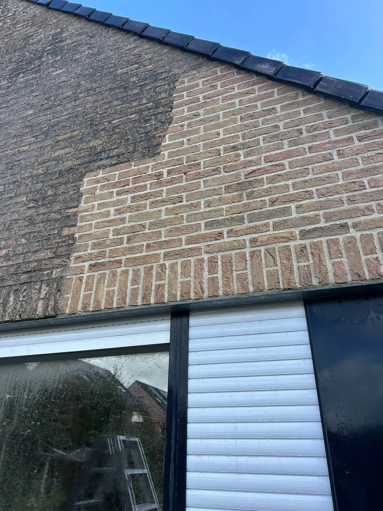 Detail van een bakstenen gevel, half gereinigd: links vervuild, rechts proper